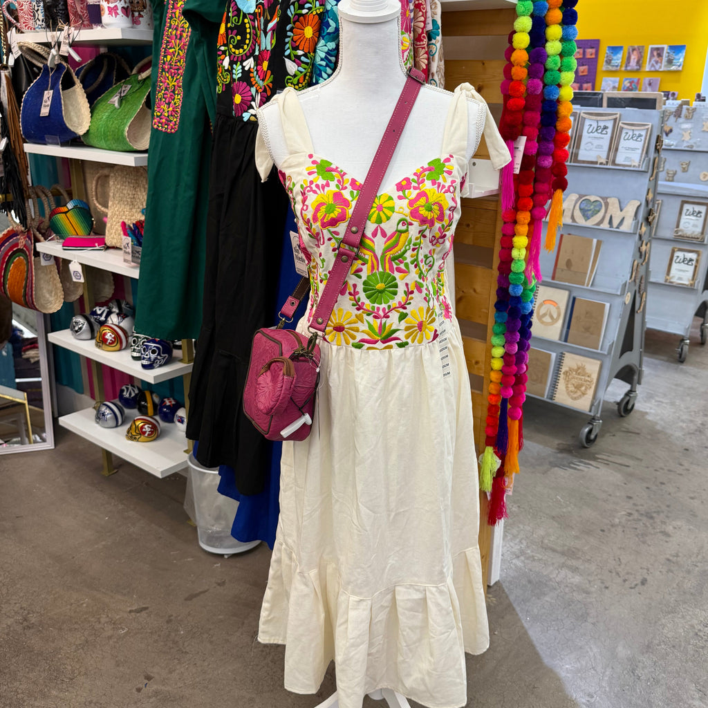 Mannequin with floral dress and accessories on a table with colorful items in the background